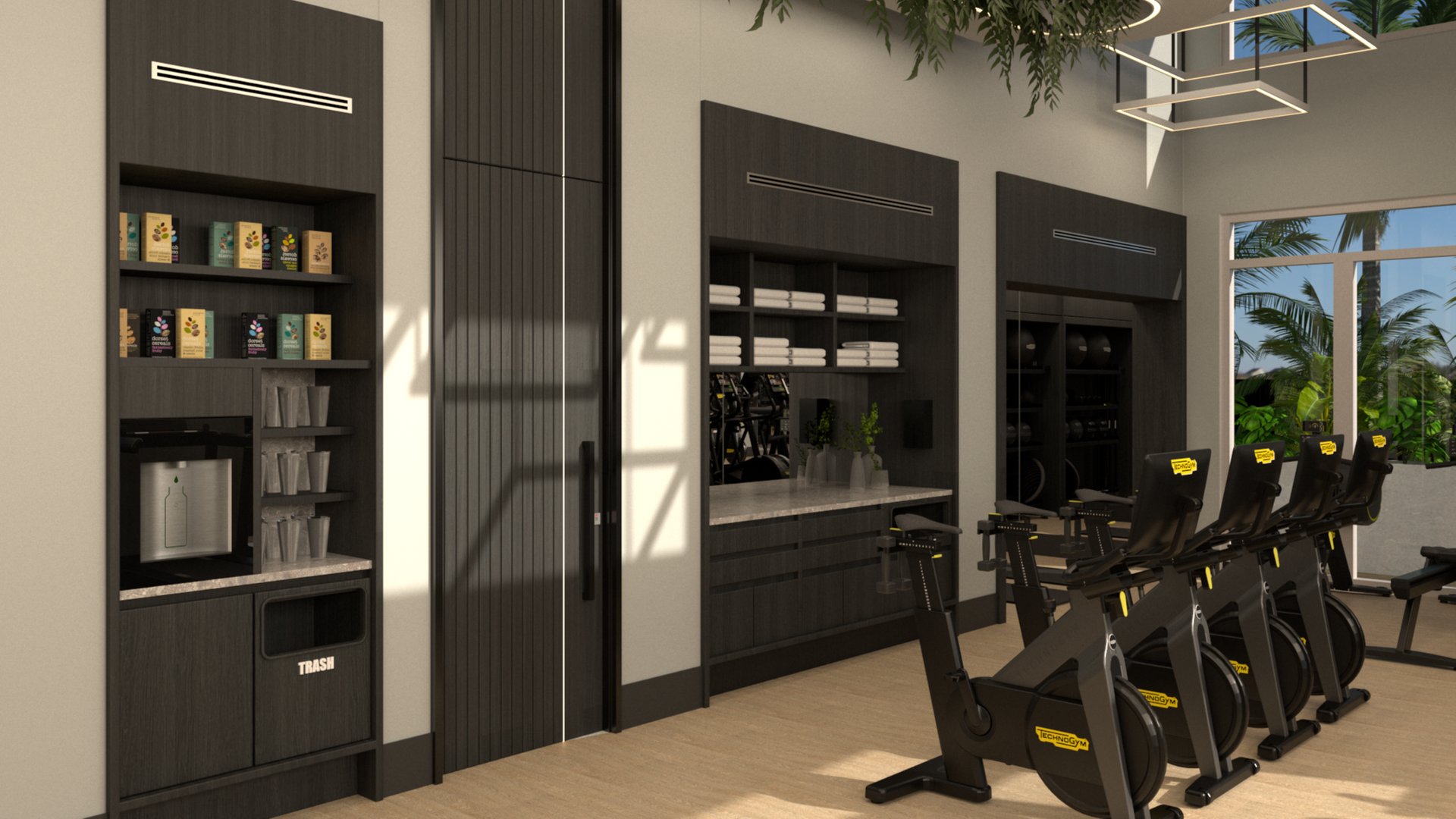 Modern gym interior with black cabinets, shelves holding towels and plants, coffee station, and four stationary bikes facing large windows with a view of palm trees and blue sky outside.