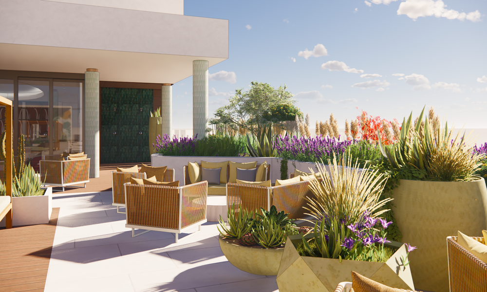 Outdoor patio with wicker chairs and green cushions, surrounded by large potted plants and colorful flowers. The area is sunny, and the sky is blue with scattered clouds. Modern building structure visible on the left.
